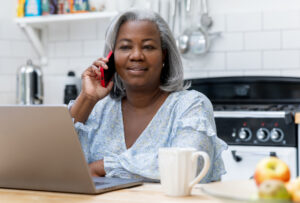 Older black woman on cell phone with laptop for healthcare patient experience