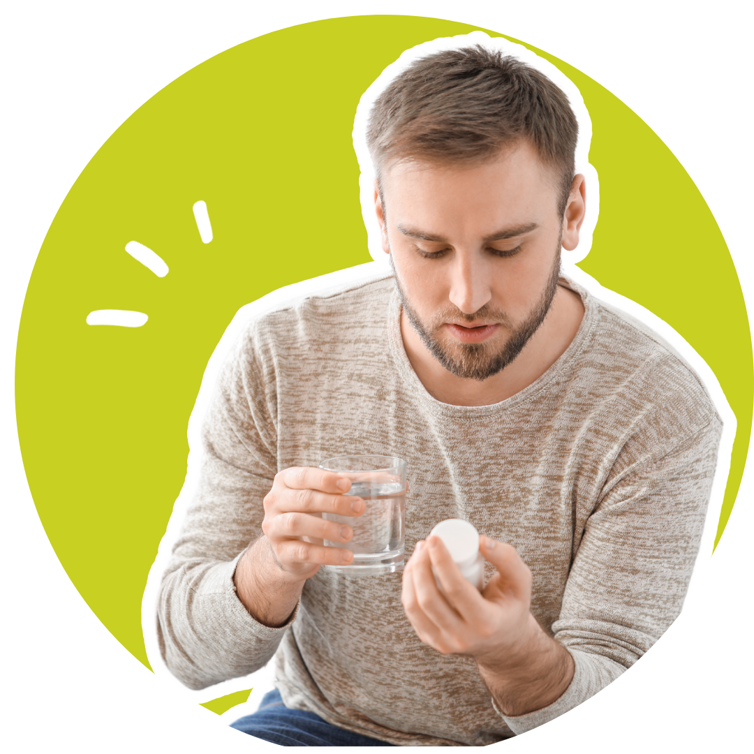man looking at a pill bottle and holding a glass of water